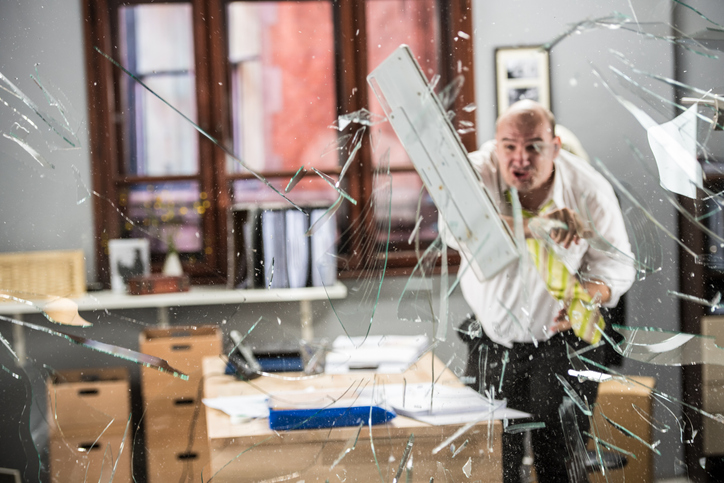 Businessman throwing keyboard on glass