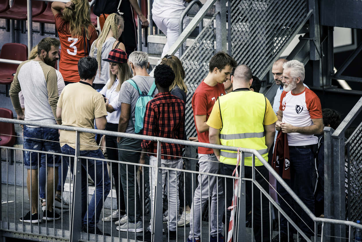 Sports fans walking up the stairs past a security guard onto the bleachers of a stadium.