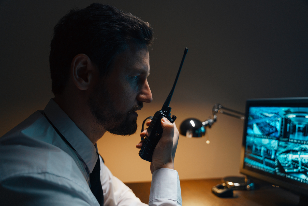 Portrait of a male security guard at the workplace. The guard is holding a walkie-talkie, he checks the security posts.