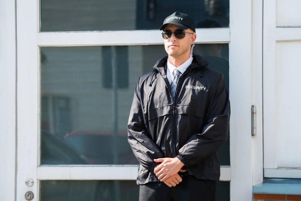 Young Male Security Guard Standing At The Entrance