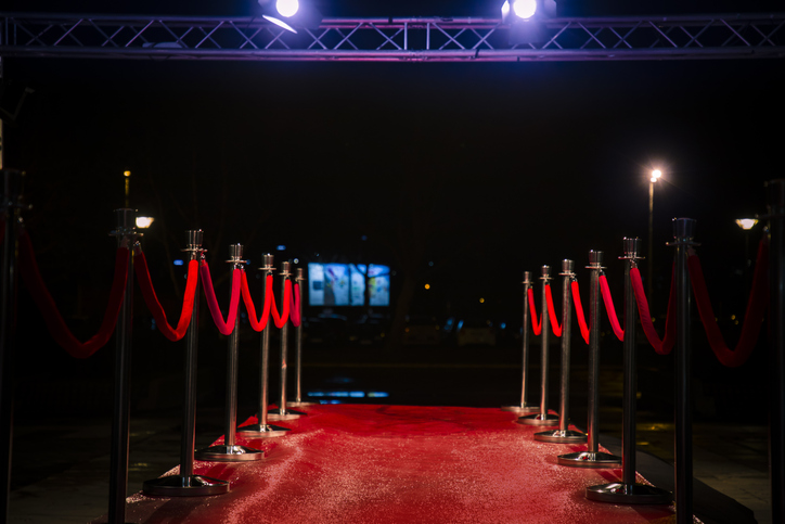 Red carpet with barriers, velvet ropes and lights in the background