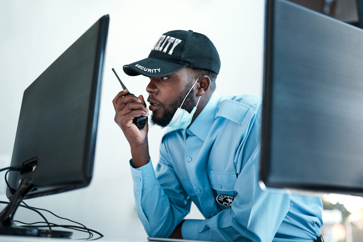 Shot of a young security guard using a two way radio while monitoring the cctv cameras