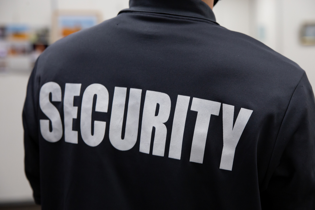 Rear view of a security guard in uniform patrolling in an art gallery in a commercial building.